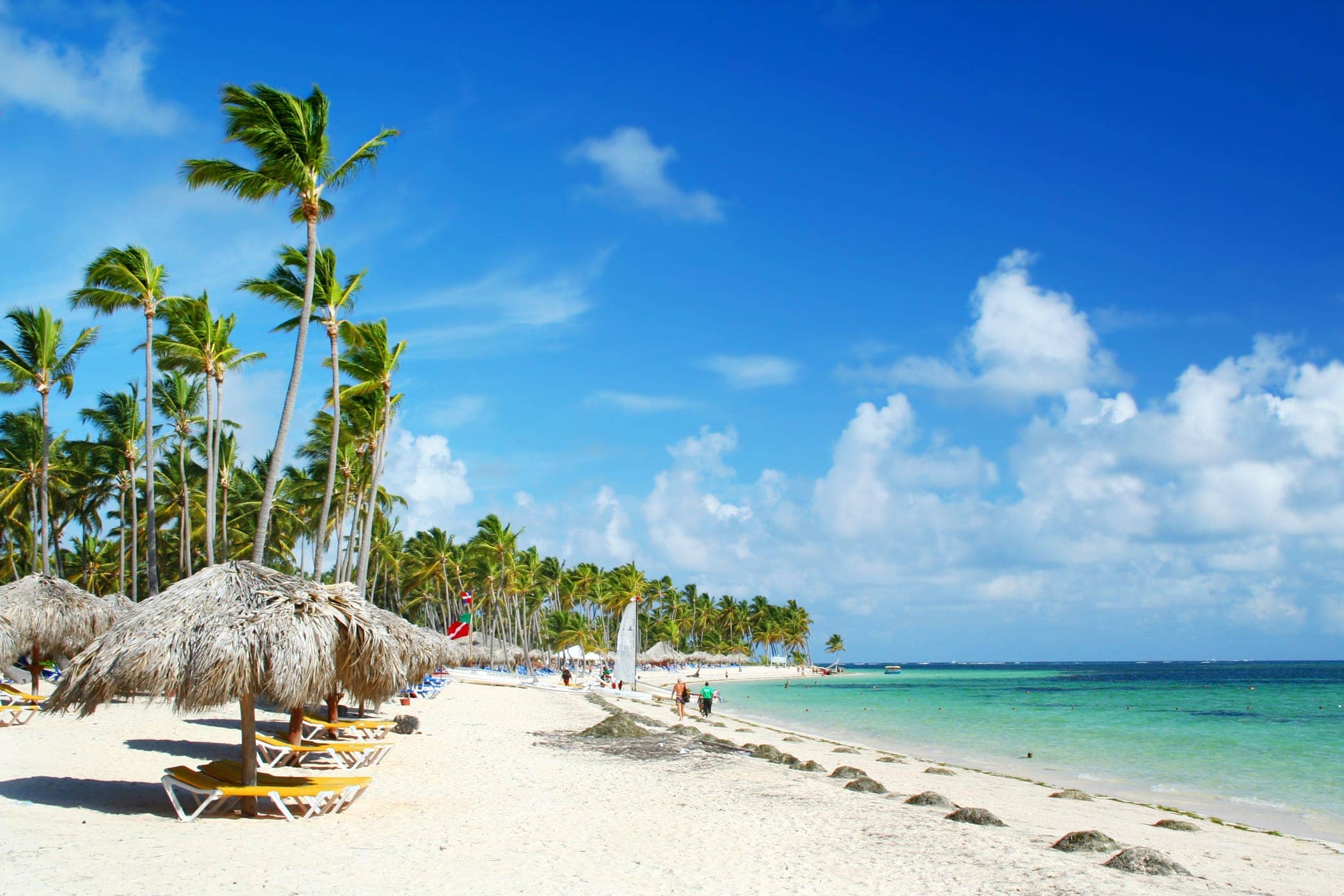 Caribbean tourist resort beach fringed grass umbrellas and beach chairs.